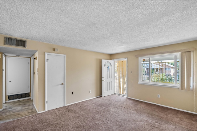 carpeted spare room with a textured ceiling