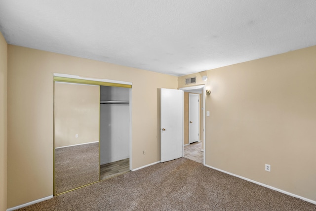 unfurnished bedroom with a textured ceiling, carpet floors, and a closet