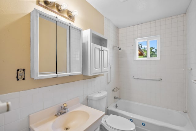 full bathroom with toilet, tiled shower / bath combo, vanity, and tile walls