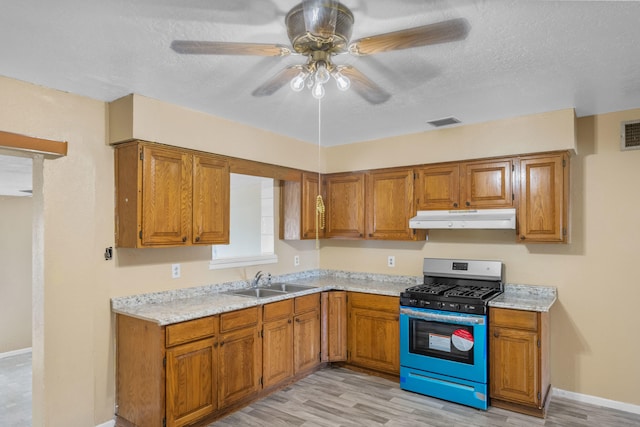 kitchen with ceiling fan, gas range, sink, and light wood-type flooring