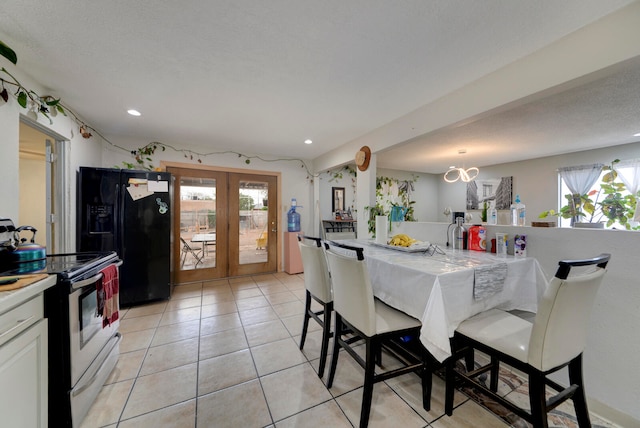 tiled dining area with french doors, a textured ceiling, and a healthy amount of sunlight