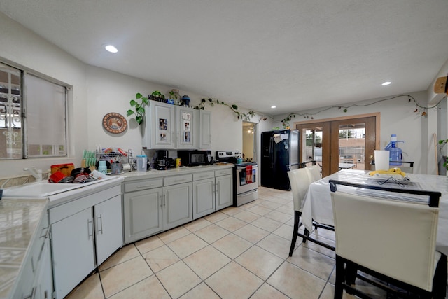 kitchen with light tile patterned floors, black appliances, sink, and white cabinets