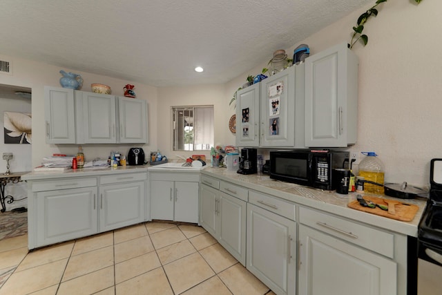 kitchen featuring white cabinetry, black appliances, and a textured ceiling