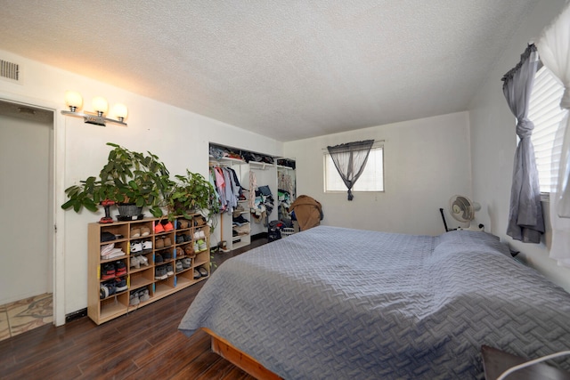 bedroom with multiple windows, a textured ceiling, and dark hardwood / wood-style flooring