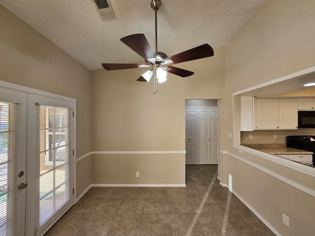 interior space featuring a textured ceiling, tile patterned flooring, french doors, and ceiling fan