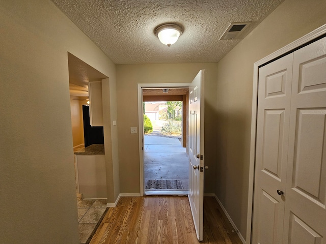 doorway to outside featuring a textured ceiling and light wood-type flooring