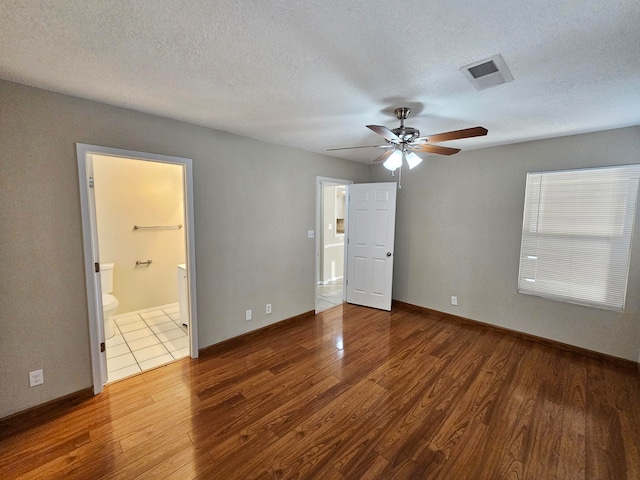 unfurnished bedroom with ceiling fan, hardwood / wood-style flooring, a textured ceiling, and ensuite bathroom