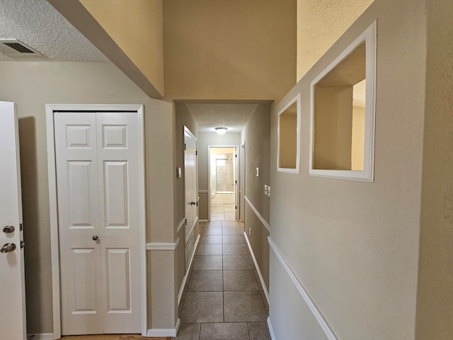 hallway with tile patterned floors and a textured ceiling