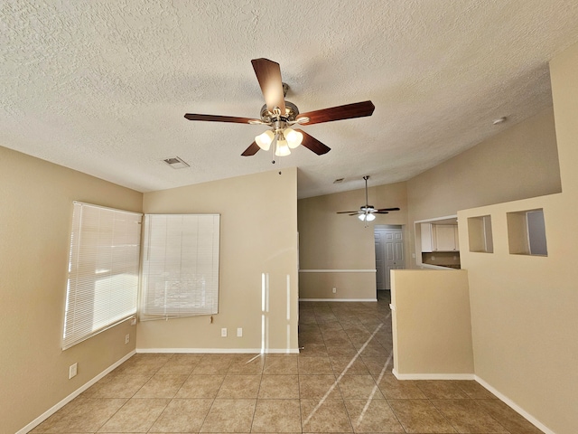 spare room with a textured ceiling, tile patterned flooring, ceiling fan, and vaulted ceiling