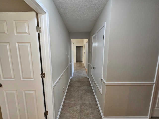 hall featuring a textured ceiling and tile patterned flooring