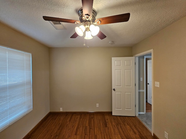 spare room featuring a textured ceiling, dark wood-type flooring, and ceiling fan