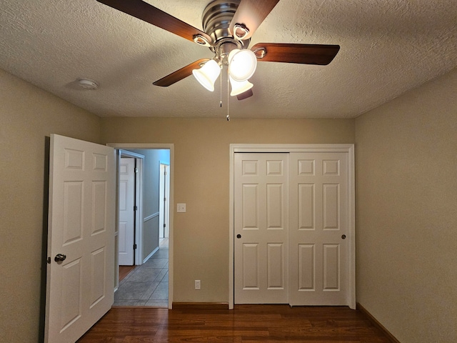 unfurnished bedroom featuring a closet, dark hardwood / wood-style floors, a textured ceiling, and ceiling fan