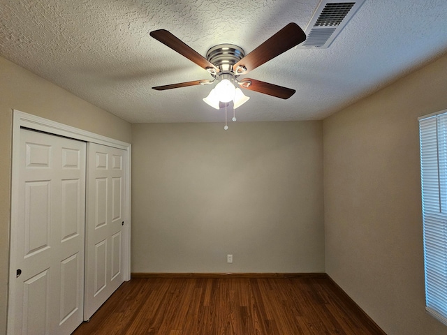 unfurnished bedroom with a closet, a textured ceiling, dark wood-type flooring, and ceiling fan