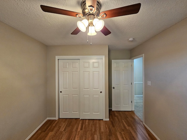 unfurnished bedroom with a closet, a textured ceiling, dark wood-type flooring, and ceiling fan