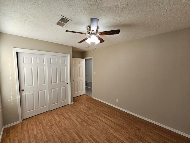 unfurnished bedroom featuring a closet, ceiling fan, a textured ceiling, and hardwood / wood-style floors