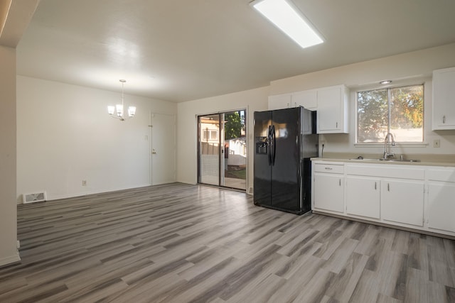 kitchen featuring sink, white cabinets, pendant lighting, and black fridge with ice dispenser