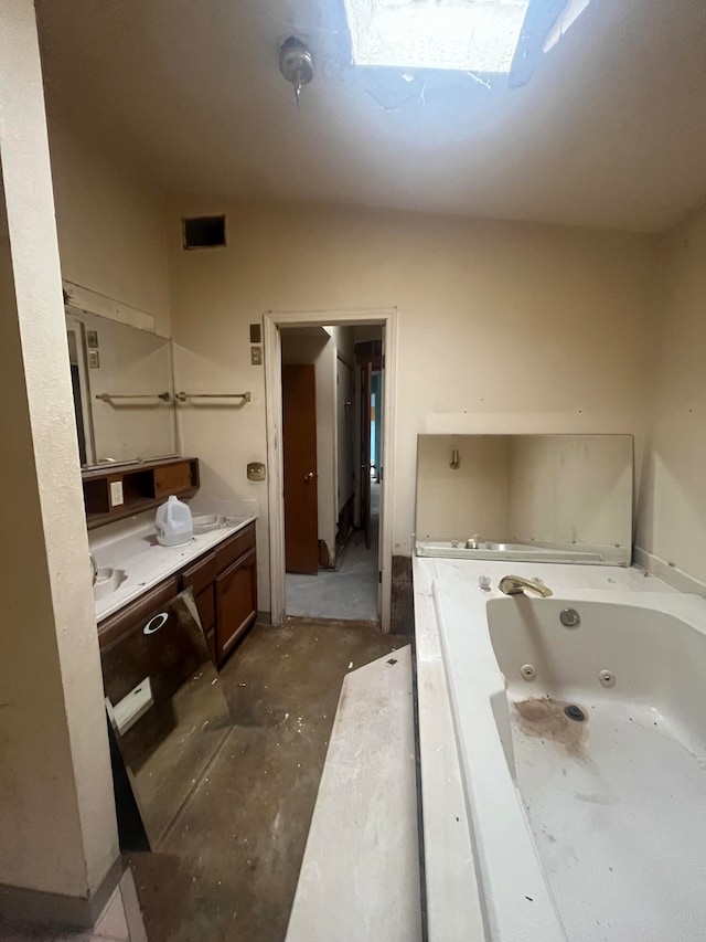 bathroom featuring vanity, a tub, concrete flooring, and a skylight