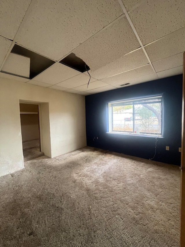 empty room featuring carpet floors and a paneled ceiling