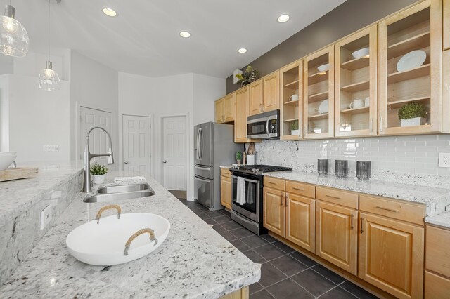 kitchen featuring light stone counters, sink, hanging light fixtures, and appliances with stainless steel finishes