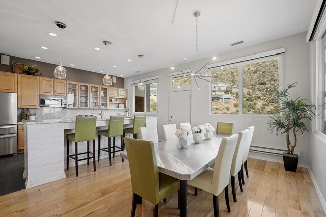 dining area featuring a chandelier, light hardwood / wood-style flooring, plenty of natural light, and sink