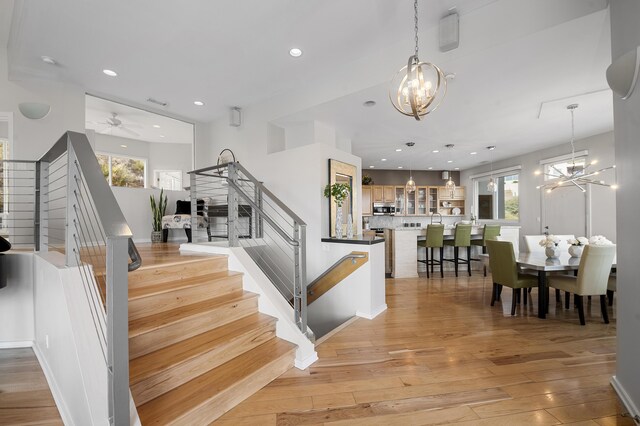 stairway featuring ceiling fan with notable chandelier and hardwood / wood-style flooring