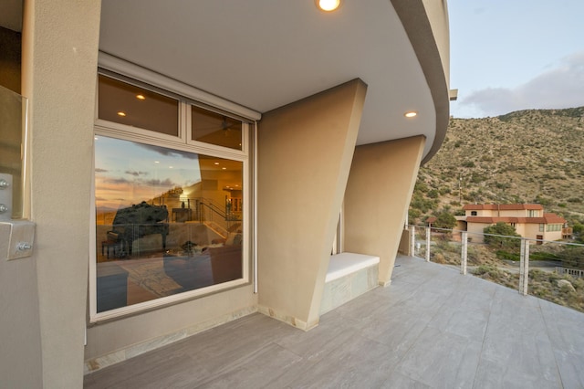 patio terrace at dusk featuring a mountain view and a balcony