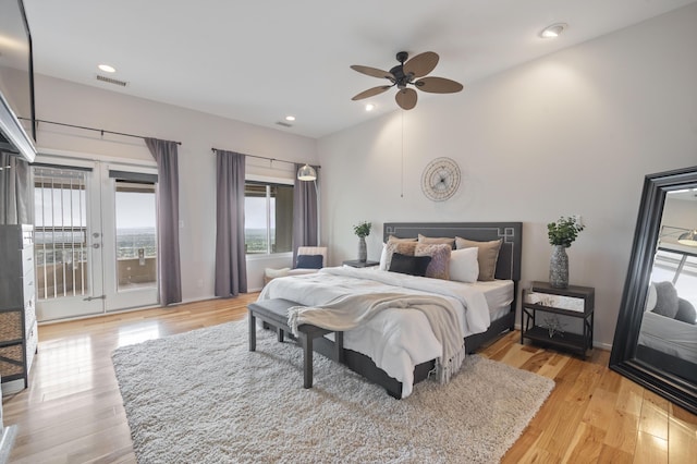 bedroom with access to outside, multiple windows, ceiling fan, and light wood-type flooring