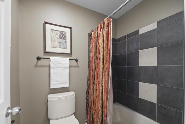 bathroom with toilet and shower / tub combo with curtain