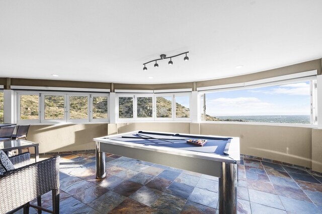 recreation room with rail lighting and a water view