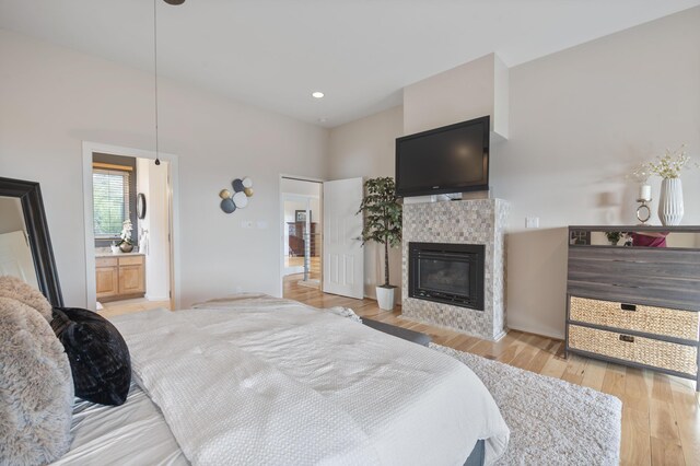 bedroom with ensuite bath, light hardwood / wood-style flooring, and a tile fireplace