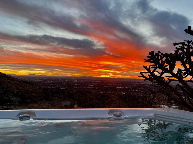 pool at dusk with a hot tub