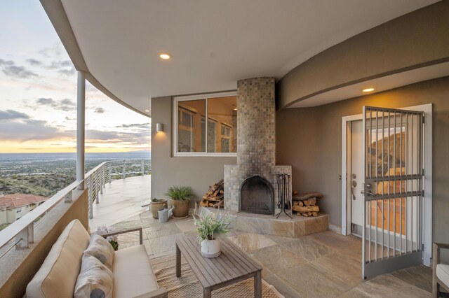 patio terrace at dusk featuring an outdoor living space with a fireplace and a balcony