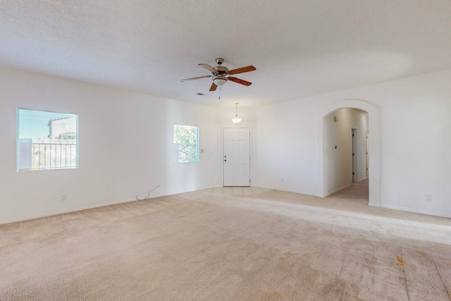 unfurnished room with a textured ceiling, light colored carpet, and ceiling fan