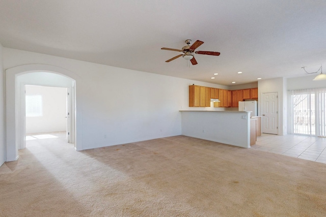 unfurnished living room featuring light carpet and ceiling fan