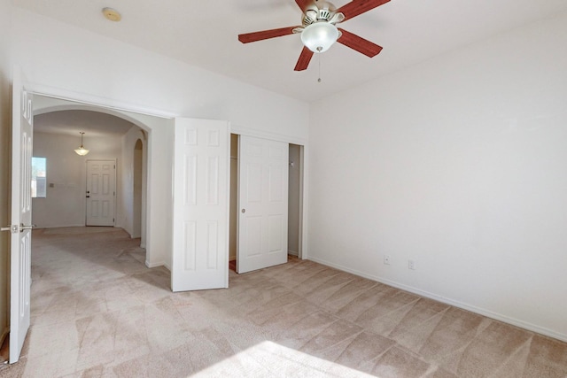 unfurnished bedroom featuring a closet, light colored carpet, and ceiling fan