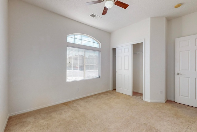 unfurnished bedroom with light carpet, a closet, a textured ceiling, and ceiling fan