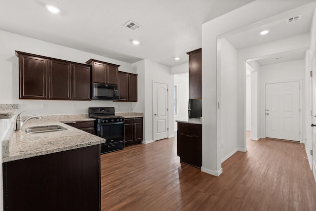 kitchen with black appliances, sink, dark brown cabinets, light stone counters, and dark hardwood / wood-style floors