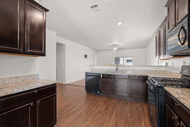 kitchen featuring dark brown cabinets, light stone counters, dark hardwood / wood-style flooring, black appliances, and sink