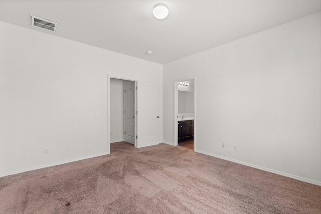 unfurnished bedroom featuring connected bathroom and light carpet