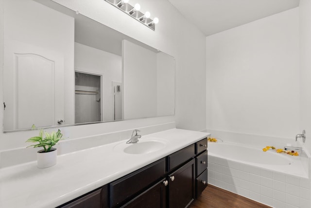 bathroom with vanity, a relaxing tiled tub, and hardwood / wood-style floors