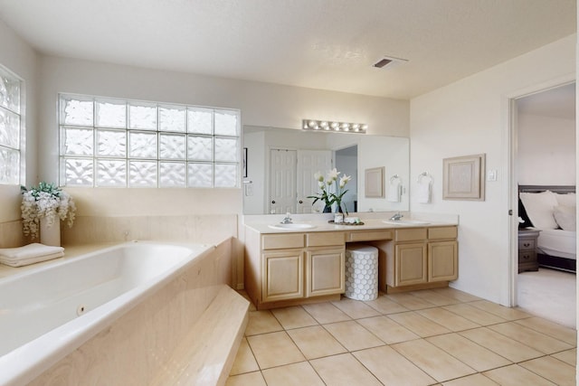 bathroom featuring a textured ceiling, vanity, tile patterned flooring, and tiled tub