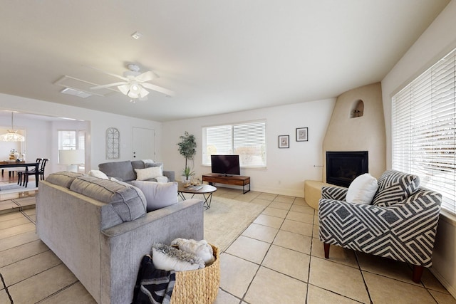 tiled living room featuring a fireplace, ceiling fan, and a healthy amount of sunlight