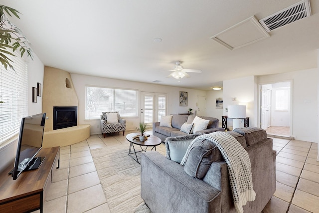 living room with ceiling fan, light tile patterned flooring, and a large fireplace