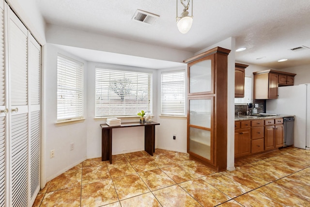 kitchen with stainless steel dishwasher, light tile patterned floors, pendant lighting, and a healthy amount of sunlight