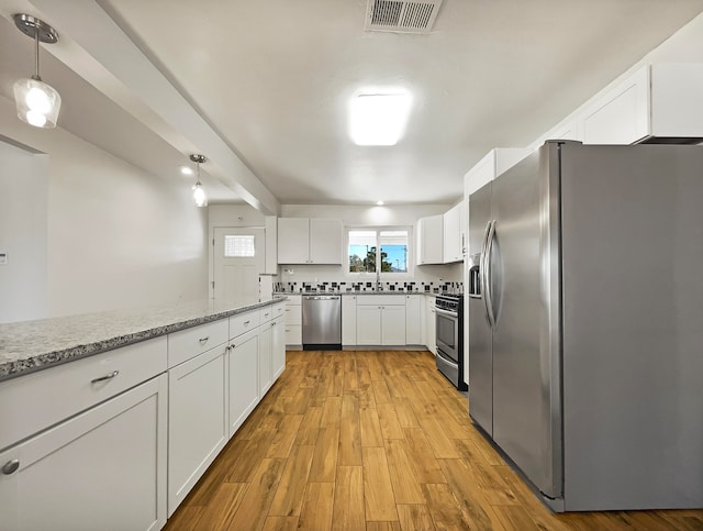 kitchen featuring white cabinets, hanging light fixtures, appliances with stainless steel finishes, light stone countertops, and light hardwood / wood-style floors