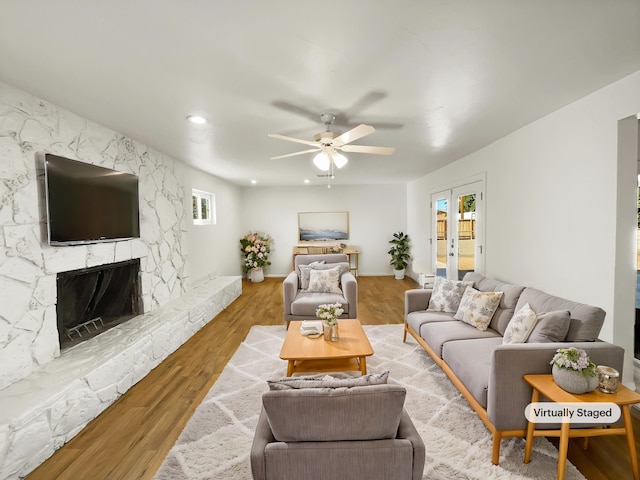 living room with hardwood / wood-style floors, french doors, a large fireplace, and ceiling fan