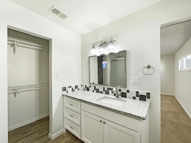 bathroom featuring vanity, hardwood / wood-style flooring, and tasteful backsplash