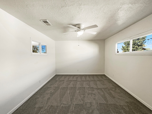 empty room with dark colored carpet, a textured ceiling, and ceiling fan