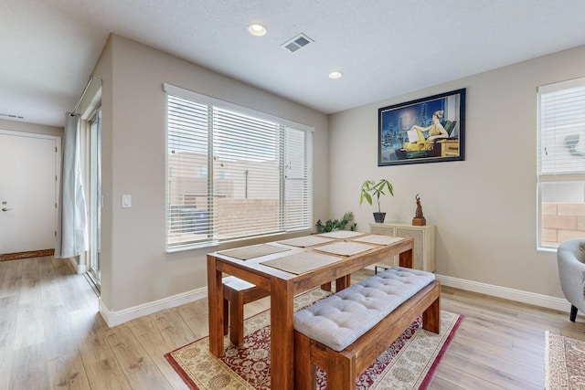 dining room with light hardwood / wood-style floors and a textured ceiling