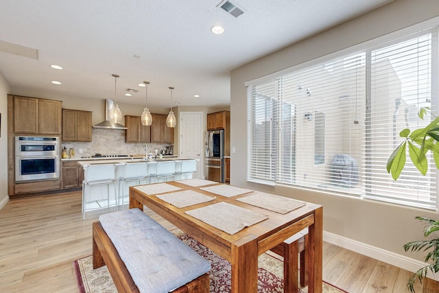 dining area featuring a wealth of natural light, light hardwood / wood-style flooring, and sink